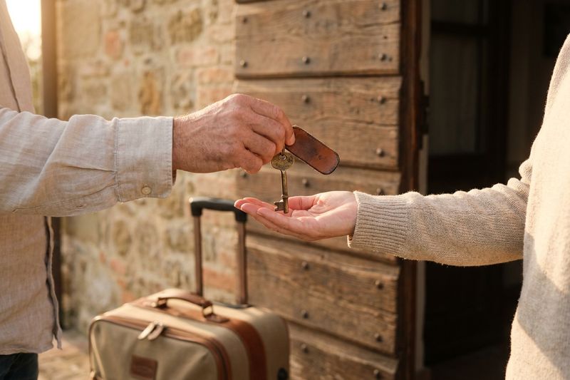 L'host consegna la chiave di casa a un ospite davanti a una porta in legno